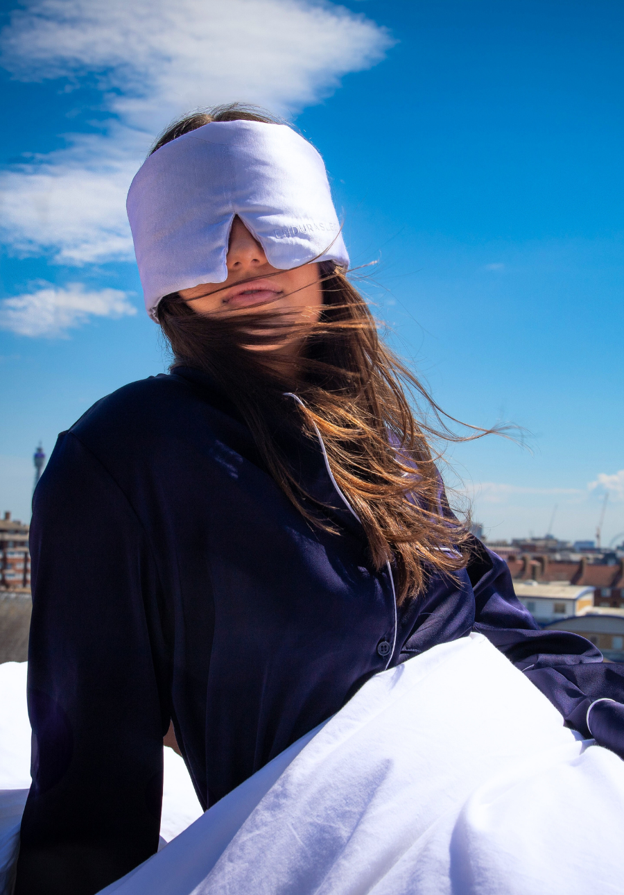 Person wearing a sleep mask on a rooftop with a cityscape in the background